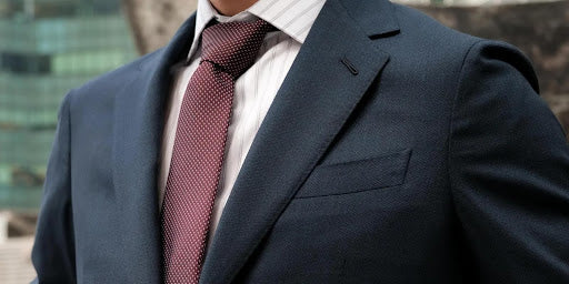 Close-up of a man wearing a dark navy bespoke suit with a burgundy tie, tailored by CYC Tailor in Singapore.