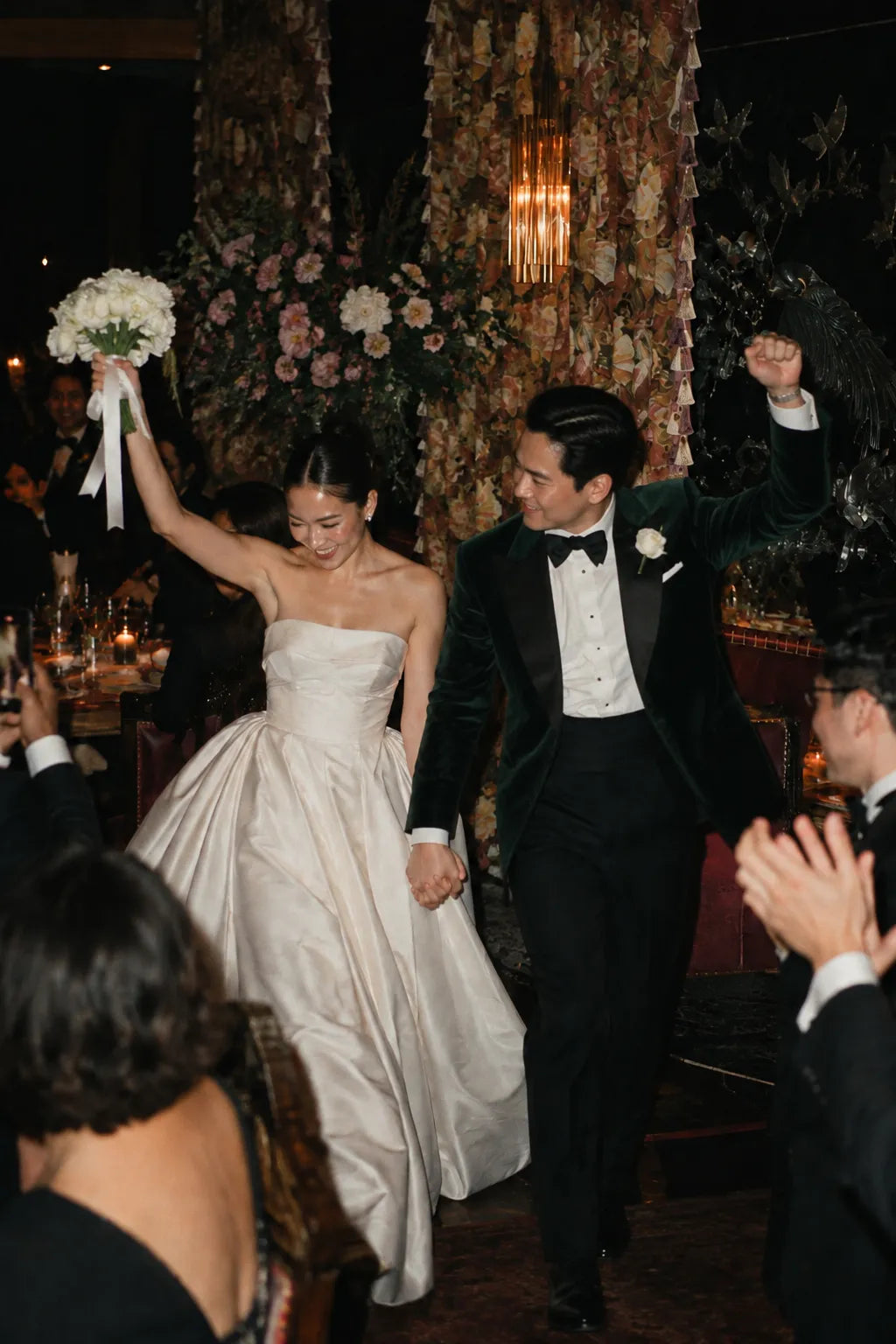 Bride and groom at a wedding banquet, with the groom wearing a black tuxedo.